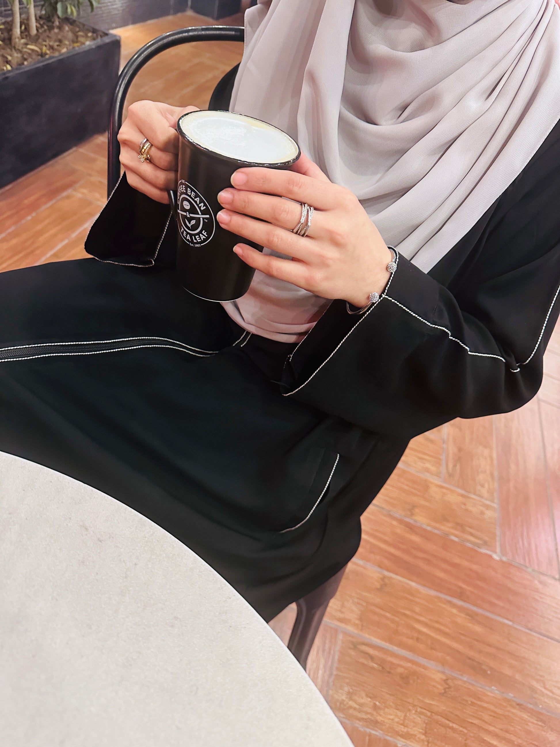 Close-up of white embroidered stitch detail on Umrah abaya