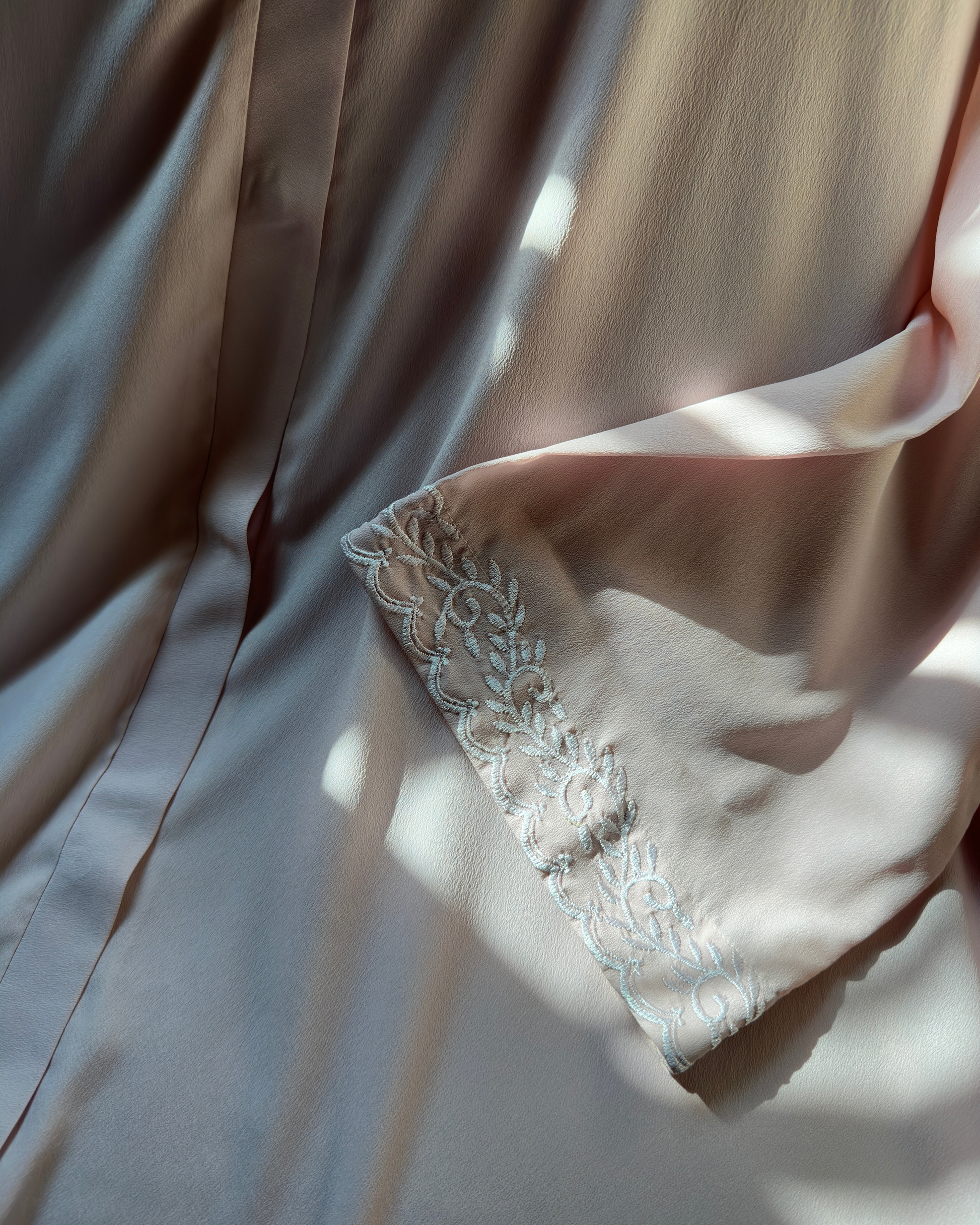 Close-up of pearl embroidery detail on light pink abaya sleeves - sophisticated modest wear